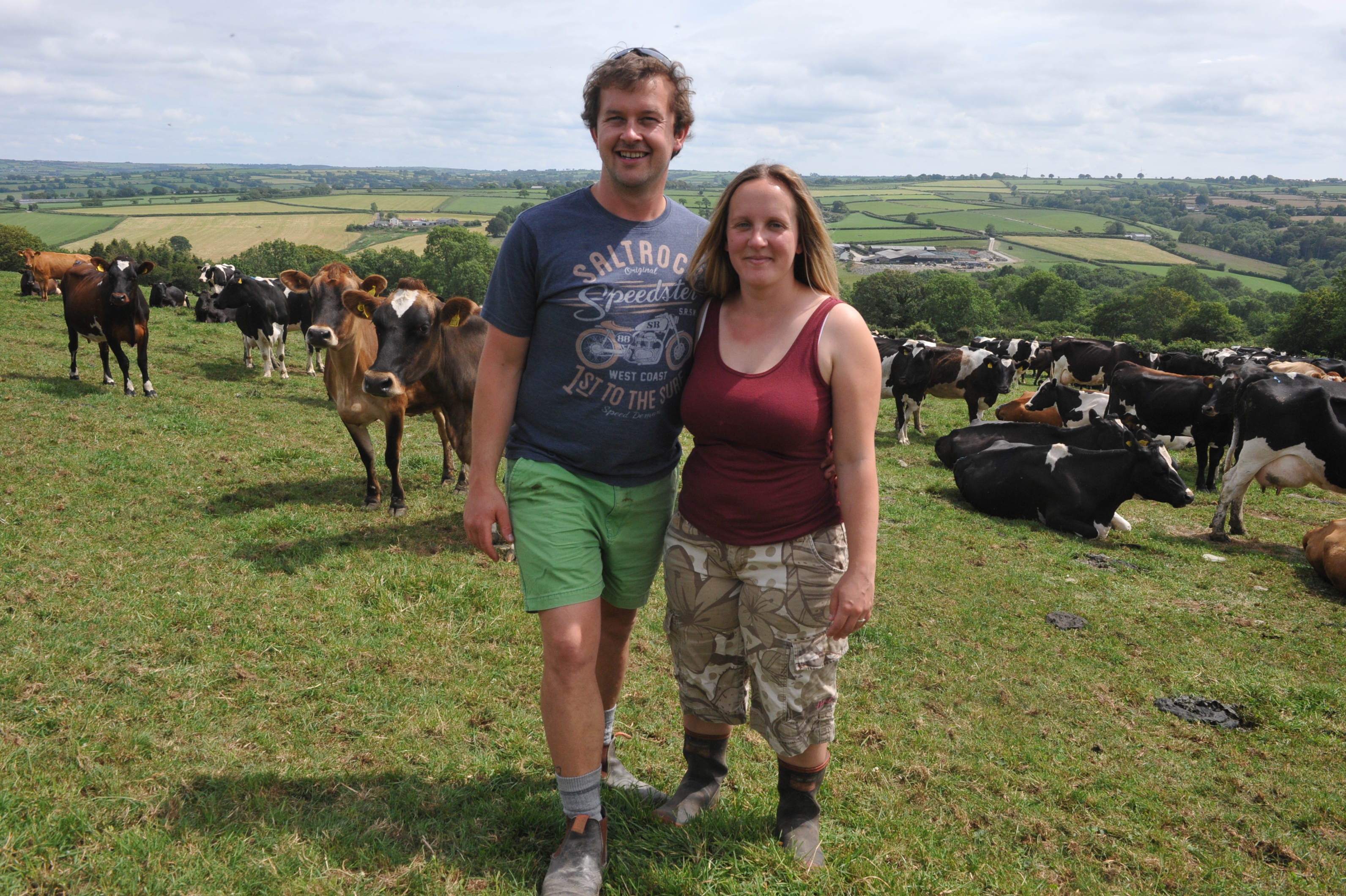 a man and woman standing in front of a herd of cows